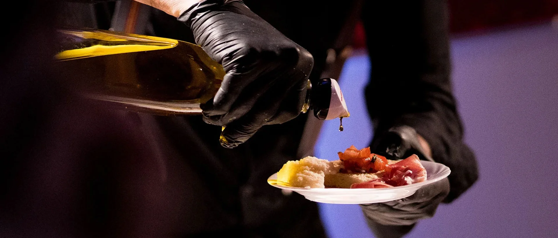 Koch träufelt Olivenöl über einen Teller mit Antipasti