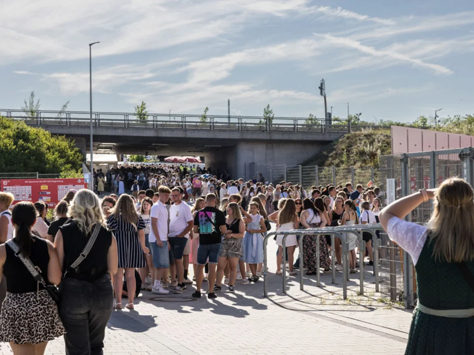 Besucher:innen warten vor dem Stadion auf den Einlass zu einem Konzert