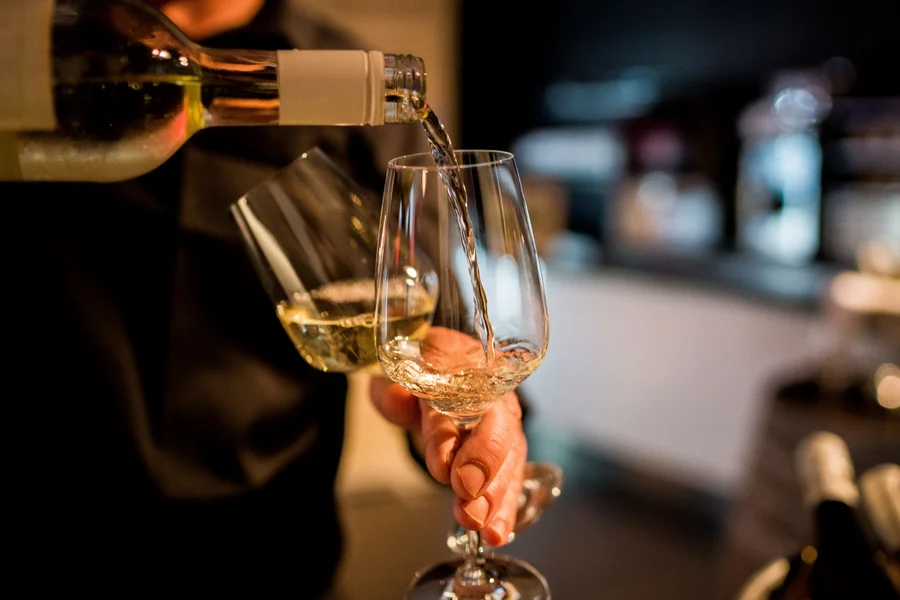 Weißwein wird an der Bar in ein Glas eingeschenkt