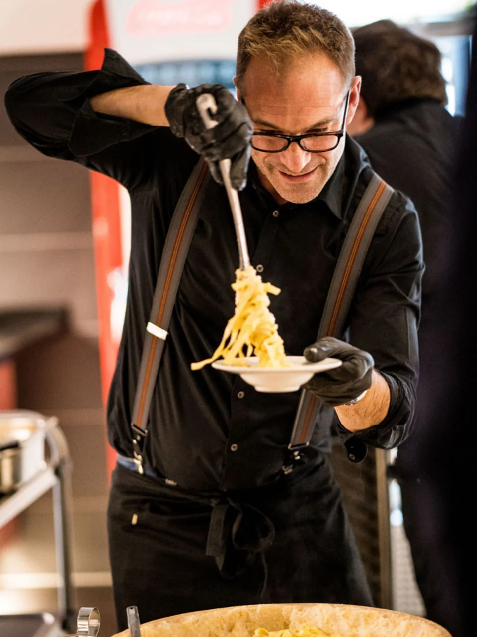 Koch richtet Pasta auf einem Teller an