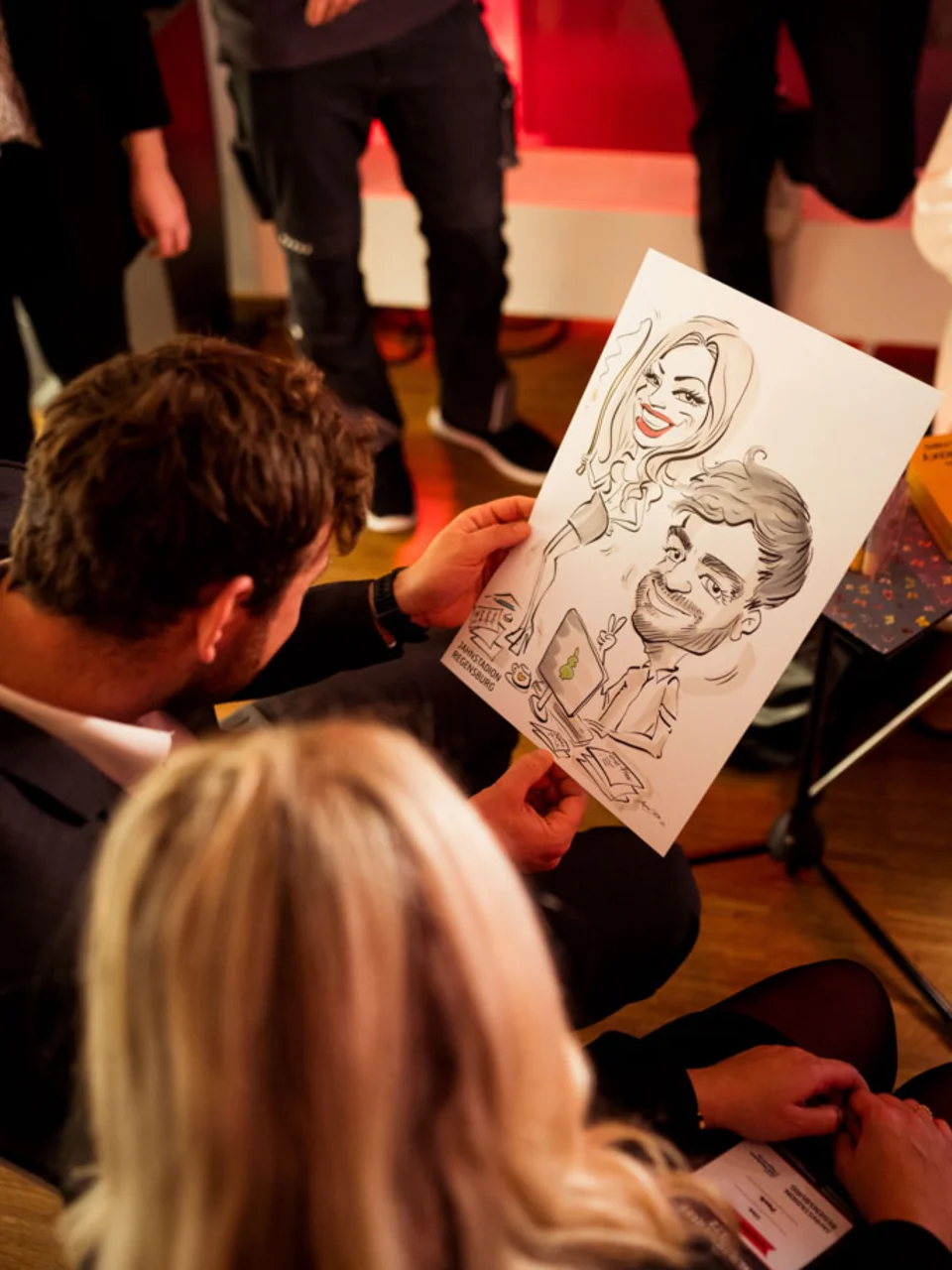 Karikaturist überreicht Gästen eine fertige Zeichnung