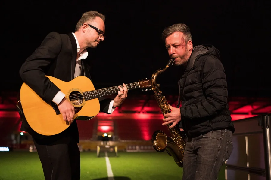 Musiker mit Gitarre und Saxofon spielen im Stadioninnenraum