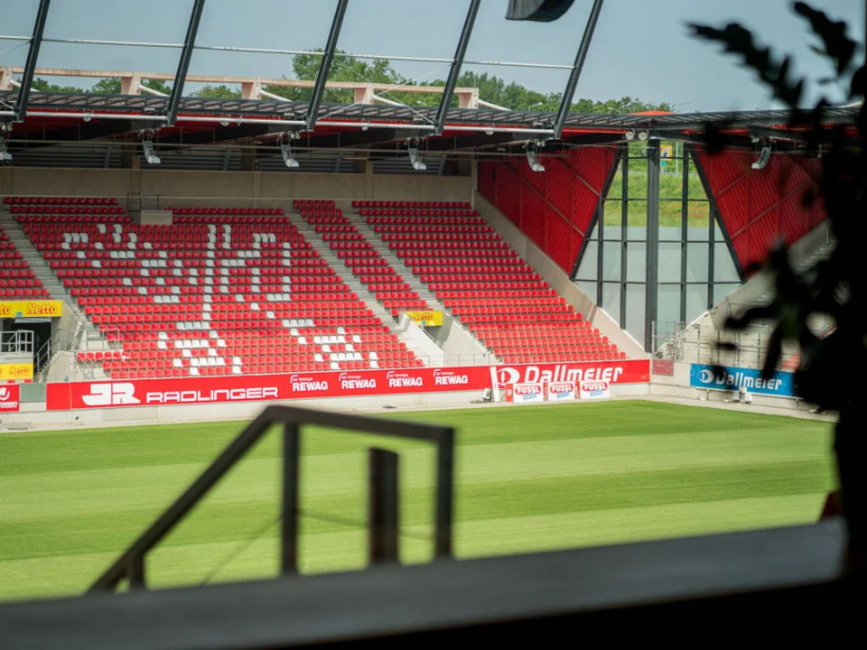 Blick durch ein Fenster auf die Tribüne und das Spielfeld