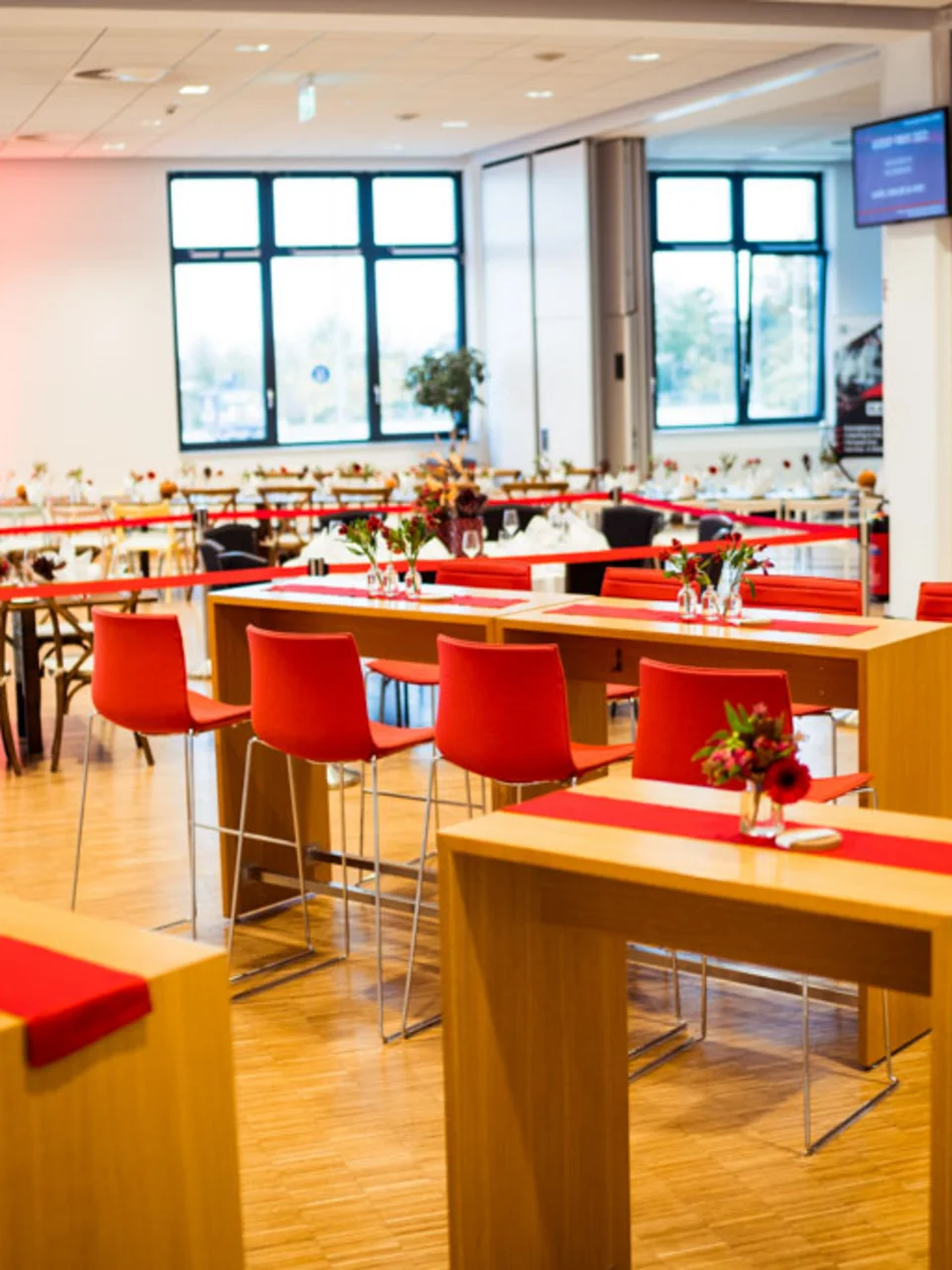 Festlich gedeckte Stehtische mit roten Barhockern im Businessclub