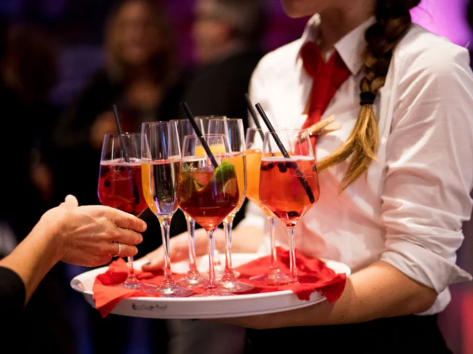 Servicekraft reicht Longdrinks auf einem Tablett