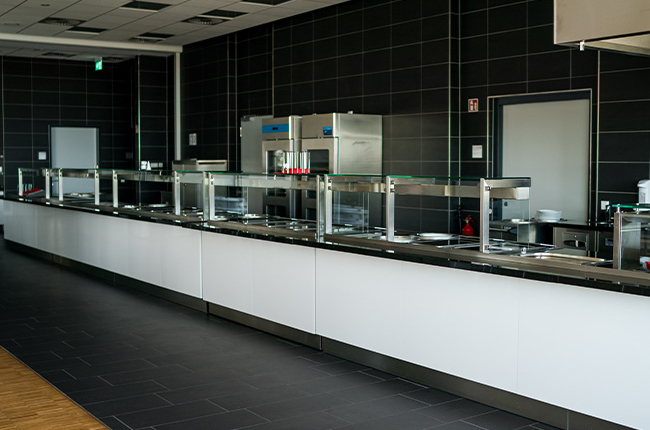 Man sieht eine leere Buffetstation, der Bereich ist am Boden und an den Wänden schwarz gefliest.