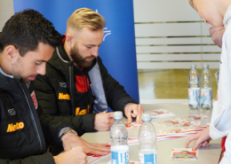 Man sieht zwei Männer, Spieler des SSV Jahn Regensburg bei einer Autogrammstunde.