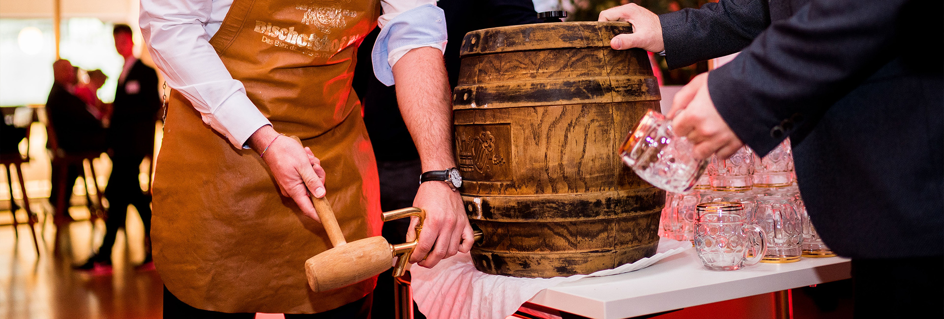 Man sieht wie ein Holzfass angezapft wird.