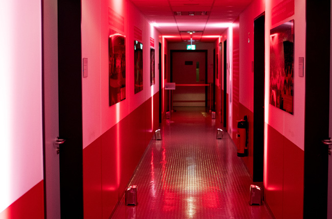 Man sieht einen rot illuminierten Gang im Jahnstadion. An der Wand hängen Bilder und die Wand ist bis zur Hälfte rot gestrichen.