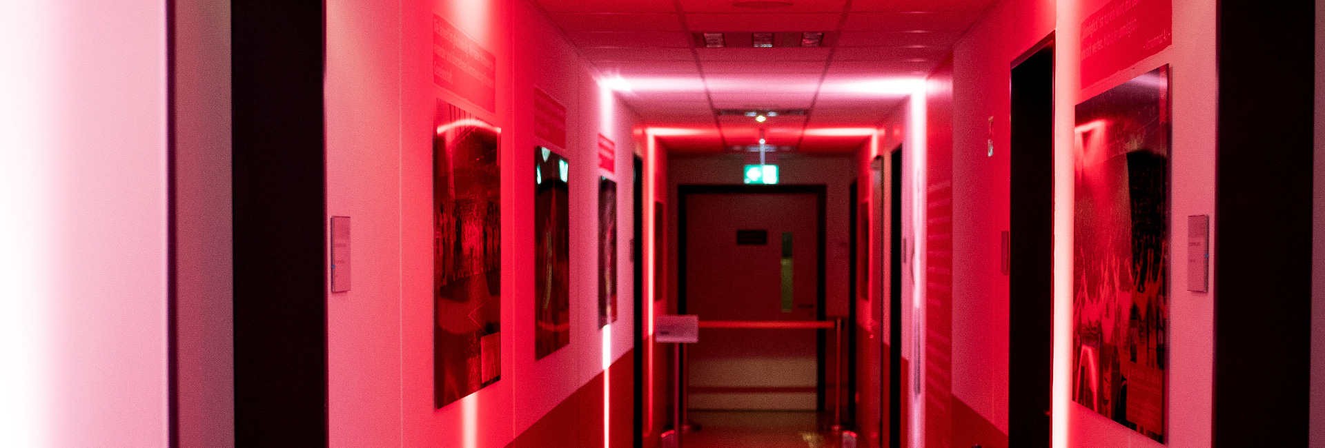 Man sieht einen rot illuminierten Gang im Jahnstadion. An der Wand hängen Bilder und die Wand ist bis zur Hälfte rot gestrichen.