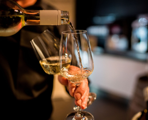 Man sieht wie eine Flasche Wein in ein Glas eingeschenkt wird.