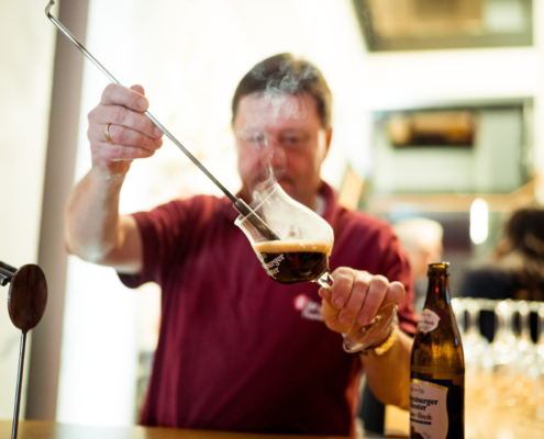 Man sieht einen Mann, der Bier in ein Glas füllt, das dampft.