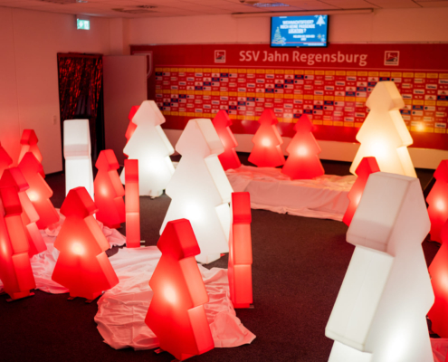 Man sieht den Presseraum im Jahnstadion mit vielen leuchtenden roten und weißen Deko-Weihnachtsbäumen.