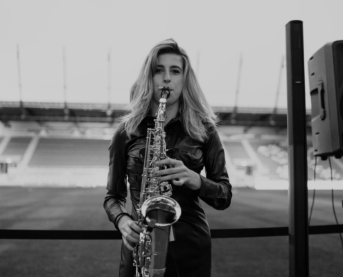 Man sieht ein schwarz-weiß Foto einer Frau, die im Jahnstadion Saxophon spielt.