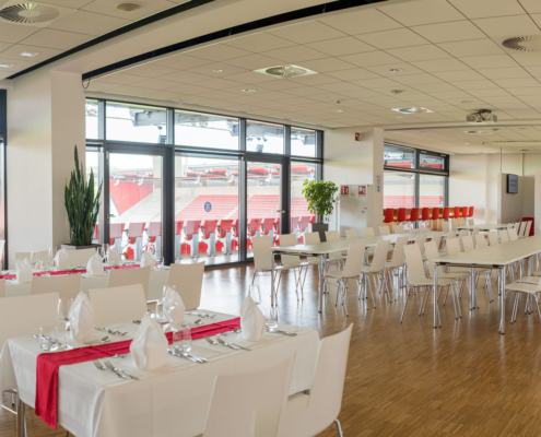 Man sieht den Innenraum des Jahnstadions Regensburg mit Blick auf den Innenraum des Stadions, dort sind vier lange weiße Tische aufgebaut.