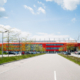 Man schaut über eine Straße auf die Längsseite des Jahnstadions. Im Hintergrund ist blau-weißer Himmel.
