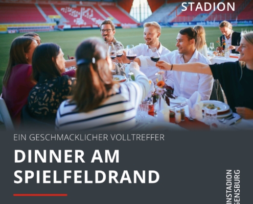 Man sieht eine Gruppe Menschen, die an einem Tisch anstoßen, der im Jahnstadion steht.