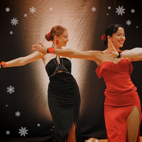 Man sieht ein Foto von zwei Frauen in rot und schwarz gekleidet, die Bachata tanzen.