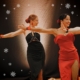 Man sieht ein Foto von zwei Frauen in rot und schwarz gekleidet, die Bachata tanzen.