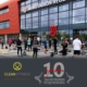 Man sieht mehrere Menschen, die vor dem Jahnstadion mit ausgelegten Yogamatten stehen und darunter das Logo von Clean Fitness und das 10 Jahre Jubiläumslogo.