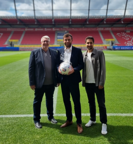 Zwei Vertreter des BFV überreichen Sebastian Graf auf dem Spielfeld im Jahnstadion Regensburg einen Fußball.