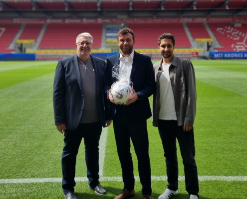 Zwei Vertreter des BFV überreichen Sebastian Graf auf dem Spielfeld im Jahnstadion Regensburg einen Fußball.