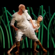 Man sieht ein Foto mit einem Mann und einer Frau auf einer Bühne mit grünem Hintergrund.